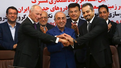 Chief Competitive Officer of Groupe Renault Thierry Bolloré, left, Chairman of Industrial Development and Renovation Oraganization of Iran, IDRO, Mansour Moazami, center, and Negin Group CEO Kourosh Morshed Solouk join hands after signing a deal in Tehran, Iran, Monday, Aug. 7, 2017. Iran signed the country's biggest-ever car deal with French multinational automobile manufacturer Groupe Renault on Monday to produce 150,000 cars, beginning in 2018.