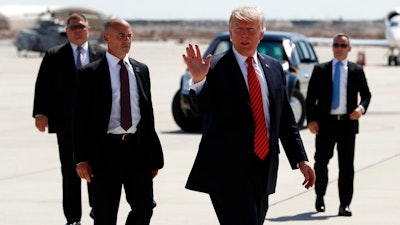 In this Tuesday, Aug. 22, 2017, file photo, President Donald Trump walks with his U.S. Secret Service protective detail as he waves before he departs on Air Force One in Yuma, Ariz. Some local officials in the border city of Yuma have expressed disappointment in the brevity of President Trump's visit, which they were hoping would give the community a higher profile on the national stage. The Yuma Sun reports that the initial plans for Trump's visit included a visit to the border and possible meetings with farmers and local politicians, but that didn't happen.