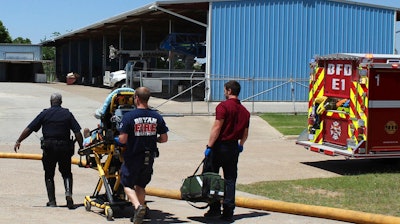 In this April 29, 2014, photo provided by the Bryan, Texas, Fire Department, firefighters transport an injured worker in a stretcher to the ambulance. An explosion at the Bryan Texas Utilities Power Plant left Earle Robinson, 60, dead and two others injured. Older people are dying on the job at a higher rate than workers overall, even as the rate of workplace fatalities decreases, according to an Associated Press analysis of federal statistics.