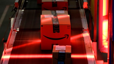 In this Tuesday, Aug. 1, 2017, photo, packages riding on a belt are scanned to be loaded onto delivery trucks at the Amazon Fulfillment center in Robbinsville Township, N.J. Amazon is holding a giant job fair Wednesday, Aug. 2, and plans to make thousands of job offers on the spot at nearly a dozen U.S. warehouses.