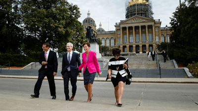 Apple CEO Tim Cook, second from left, and Iowa Gov. Kim Reynolds, third from left, walk to a podium in front of the Capitol building, background, in Des Moines, Iowa, Thursday, Aug. 24, 2017, to announce Apple's plans for two new data storage centers and to create at least 50 jobs near Des Moines.