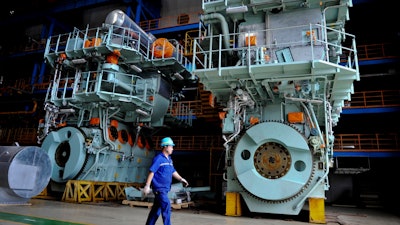 In this Tuesday, Aug. 29, 2017 photo, a worker walks by engine parts at a production base of China Shipbuilding Industry Corporation (CSIC) Diesel Engine Co. Ltd. in Qingdao in east China's Shandong province. An official survey released Thursday, Aug. 31 shows Chinese manufacturing activity picked up pace in August, indicating a crucial component of the world's second-biggest economy is holding firm.