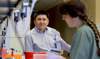 In this July 31, 2017 photo provided by Oregon Health & Science University, Shoukhrat Mitalipov, left, talks with research assistant Hayley Darby in the Mitalipov Lab at OHSU in Portland, Ore. Mitalipov led a research team that, for the first time, used gene editing to repair a disease-causing mutation in human embryos, laboratory experiments that might one day help prevent inherited diseases from being passed to future generations.