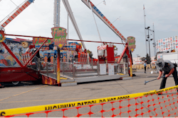 In this July 27, 2017 file photo, an Ohio State Highway Patrol trooper removes a ground spike in front of the fire ball ride at the Ohio State Fair in Columbus, Ohio. The Dutch manufacturer of a thrill ride that broke apart and killed an 18-year-old man at the Ohio State Fair says excessive corrosion on a support beam led to a “catastrophic failure.” A statement on KMG’s website dated Friday, Aug. 4, says the company officials visited the accident site and conducted metallurgical tests.