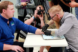 Tony Danna, left, vice president of international development at Three Square Market in River Falls, Wis., receives a microchip in his left hand at company headquarters Tuesday, Aug. 1, 2017. The company is making microchips available to its employees, allowing them to open doors, log onto their computers or buy breakroom snacks by simply waving their hand.