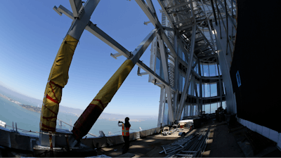 In this photo taken Tuesday, July 11, 2017, a woman looks out toward the San Francisco-Oakland Bay Bridge from just below the top of the Salesforce Tower in San Francisco. Construction crews are putting the finishing touches on San Francisco’s new tallest building. The 61-story Salesforce Tower and an adjacent transit center represent a shift in San Francisco, one that pits the technology industry against the city’s charming neighborhoods.