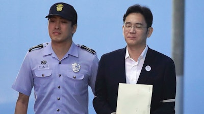 Samsung Electronics Co. Vice Chairman Lee Jae-yong, right, leaves after his verdict trial at the Seoul Central District Court Friday, Aug. 25, 2017 in Seoul, South Korea. The court sentenced the billionaire Samsung heir to five years in prison for bribery and other crimes that fed public anger leading to the ouster of Park Geun-hye as South Korea's president.