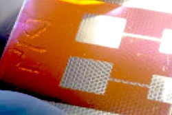 A compound solar cell illuminated from a light source below. Hexagonal scaffolds are visible in the regions coated by a silver electrode. The new solar cell design could help scientists overcome a major roadblock to the development of perovskite photovoltaics.