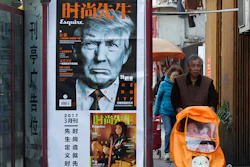In this March 15, 2017 file photo, a man pushes a stroller past a magazine advertisement featuring U.S. President Donald Trump at a news stand in Shanghai, China. U.S. media reported Wednesday, Aug 2, 2017 that the administration of President Donald Trump is considering using rarely invoked U.S. trade laws to compel China to crack down on theft of copyrights, patents and other intellectual property and fend off technology sharing demands from Beijing.