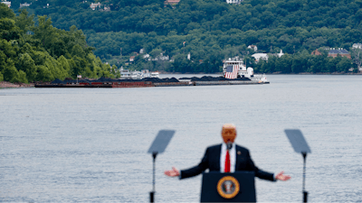 In this June 7, 2017 file photo, a coal barge is positioned as a backdrop behind President Donald Trump as he speaks during a rally at the Rivertowne Marina in Cincinnati. President Donald Trump personally promised to activate emergency legal authorities to keep dirty or economically uncompetitive coal plants from shutting down, a top American coal company said. The Trump administration now says it has no plans to do so.