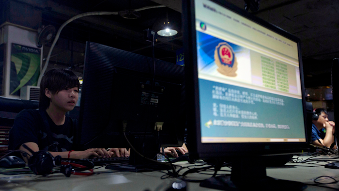In this Aug. 19, 2013 file photo, computer users sit near a monitor display with a message from the Chinese police on the proper use of the Internet at an Internet cafe in Beijing, China. China's campaign to stamp out use technology that allows web surfers to evade its internet filters is disrupting work and study for entrepreneurs, scientists and students. The crackdown comes as the ruling Communist Party tightens political control ahead of a congress at which President Xi Jinping is due to be appointed to a second 5-year term as leader.