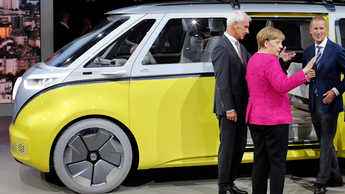 German Chancellor Angela Merkel, center, VW group CEO Matthias Mueller, left, and VW Cars CEO Herbert Diess, right, stay beside a 'VW I.D. Buzz' concept car at the booth of the German car manufacturer Volkswagen during Merkel's visit at the Frankfurt Auto Show IAA in Frankfurt, Germany, Thursday, Sept. 14, 2017.