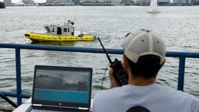 In this Aug. 15, 2017 photo, computer scientist Mohamed Saad Ibn Seddik, of Sea Machines Robotics, uses a laptop to guide a boat outfitted with sensors and self-navigating software and capable of autonomous navigation in Boston Harbor. The boat still needs human oversight, but some of the world's biggest maritime firms have committed to designing ships that won't need any captains or crews - at least not on board.