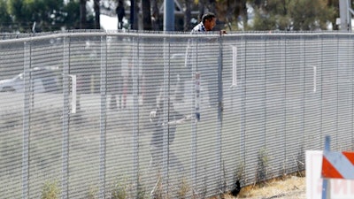 A man is detained by Border Patrol officials as he tries to climb a fence after breaching border fencing separating San Diego from Tijuana, Mexico, Tuesday, Sept. 26, 2017, in San Diego. The man, who said he was from Chiapas, Mexico, was detained by agents as they prepared for a news conference to announce that contractors have begun building eight prototypes of President Donald Trump's proposed border wall with Mexico.