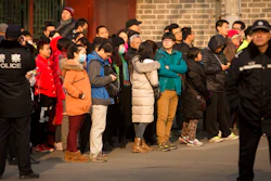 In this Jan. 1, 2016, file photo, policemen watch as depositors from Ezubo gather outside the State Bureau for Letters and Calls Reception Division office in Beijing. The founder of a Chinese online peer-to-peer lender has been sentenced to life in prison Tuesday, Sept. 12, 2017, on charges he defrauded investors of $7.7 billion in one of China's biggest financial scams.