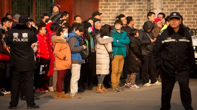 In this Jan. 1, 2016, file photo, policemen watch as depositors from Ezubo gather outside the State Bureau for Letters and Calls Reception Division office in Beijing. The founder of a Chinese online peer-to-peer lender has been sentenced to life in prison Tuesday, Sept. 12, 2017, on charges he defrauded investors of $7.7 billion in one of China's biggest financial scams.