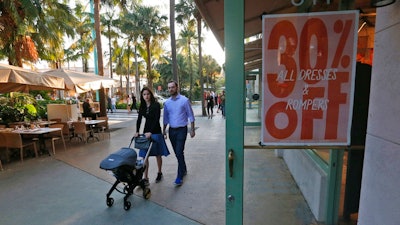 In this Wednesday, April 26, 2017, photo, pedestrians walk past a store on Miami Beach, Florida's Lincoln Road. American consumers feel a bit less confident in September 2017, their spirits pulled down by Hurricanes Harvey and Irma, according to consumer confidence index information released Tuesday, Sept. 26, 2017, by the Conference Board.