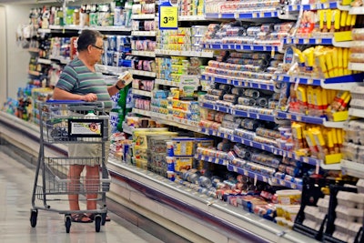 In this June 17, 2014, file photo, a shopper looks at an item in the dairy section of a Kroger grocery store in Richardson, Texas. Some of the world’s biggest consumer goods companies have agreed to simplify food date labels that create confusion among shoppers and leads them to discard billions of dollars’ worth of food. The goal: to streamline the labels, including “Sell by” and “Display Until,” down to two by 2020, says The Consumer Goods Forum.