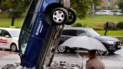 A Volkswagen Touareg stands upside down in front of the fair ground of the IAA Motor Show in Frankfurt, Germany, Wednesday, Sept. 13, 2017. The environmental organization Greenpeace installed the car the day before to protest against the car industry. From frighteningly fast hypercars to new electric SUVs, the Frankfurt auto show is a major event for car lovers wanting to get a glimpse of the future.