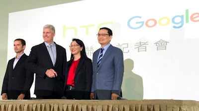 Rick Osterloh, senior vice president of hardware for Google, second from left, and Cher Wang, chairperson of HTC, shake hands during a press conference in New Taipei City, Taiwan, Thursday, Sept. 21, 2017. Google is biting off a big piece of device manufacturer HTC for $1.1 billion to expand its efforts to build phones, speakers and other gadgets equipped with its arsenal of digital services. At left is Mario Queiroz, vice president of product management at Google, and at right is Chia-Lin Chang, president of smartphones and connected devices for HTC.