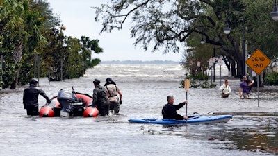 Rescue workers, left, search a neighborhood for flood victims as a man on a kayak down the street after Hurricane Irma brought floodwaters to Jacksonville, Fla. Monday, Sept. 11, 2017.