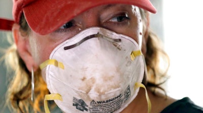 Volunteer Adrienne Adair wears a mask while helping clean up damage from Hurricane Harvey Sunday, Sept. 3, 2017, in Spring, Texas.