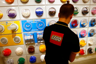 In this Tuesday, April 5, 2016 file photo, an employee sorts Legos in the the new LEGO flagship store unveiled as part of the new Les Halles shopping mall during the press visit in Paris. Danish toy maker Lego said Tuesday, Sept. 5, 2017, it will cut 1,400 jobs, or about eight percent of its global workforce, after reporting a decline in sales and profits in the first half of 2017.