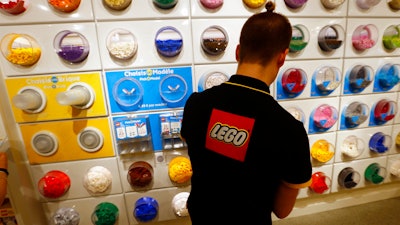 In this Tuesday, April 5, 2016 file photo, an employee sorts Legos in the the new LEGO flagship store unveiled as part of the new Les Halles shopping mall during the press visit in Paris. Danish toy maker Lego said Tuesday, Sept. 5, 2017, it will cut 1,400 jobs, or about eight percent of its global workforce, after reporting a decline in sales and profits in the first half of 2017.