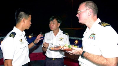 This July 4, 2001, file photo provided by the U.S. Department of Defense shows U.S. Navy Commander Dave Kapaun, right, with Republic of Singapore Navy Major Danny Tan, left, and Republic of Singapore Major H .C. Lim at a reception on board the U.S. Navy dock landing ship USS Rushmore during the seventh annual Cooperation Afloat Readiness and Training (CARAT) Exercise. Retired U.S. Navy Commander Kapaun,who pleaded guilty to lying about his relationship with a Malaysian defense contractor nicknamed 'Fat Leonard' is facing sentencing.