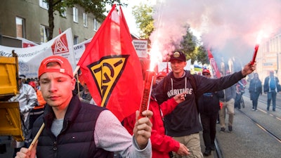 Demonstrators hold Bengal flare during a protest in Bochum, western Germany, Friday, Sept. 22, 2017. Thousands of steelworkers have gathered in a protest over the planned merger of the European steel operations of Thyssenkrupp and Tata Steel, which is expected to cost up to 4,000 jobs.