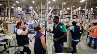 In this June 6, 2017 photo, Evens Presendeaux of Haiti speaks with coworkers on the floor of a factory in Tijuana, Mexico. Presendeaux is among about 4,000 Haitians to establish roots in Mexico's northwest corner after the United States abruptly closed its doors late last year. The Mexican government has welcomed them, and they are already having an outsize economic and cultural impact.