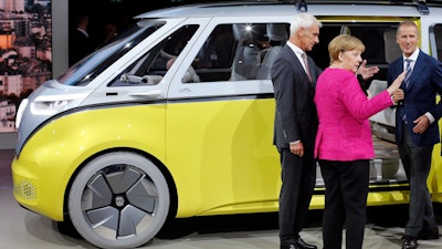 German Chancellor Angela Merkel, center, VW group CEO Matthias Mueller, left, and VW Cars CEO Herbert Diess, right, stay beside a 'VW I.D. Buzz' concept car at the booth of the German car manufacturer Volkswagen during Merkel's visit at the Frankfurt Auto Show IAA in Frankfurt, Germany, Thursday, Sept. 14, 2017.