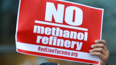 A citizen holds a sign as he protests in Tacoma outside a public meeting to gather opinion on a proposed methanol plant that would be built at the Port of Tacoma.