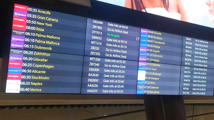 Monarch Airlines passengers are directed to the airline desk at London's Gatwick Airport, Monday, Oct. 2, 2017. Troubled British carrier Monarch Airlines has suspended flights after failing to resolve its financial woes. The airline, the country's fifth largest, stopped trading on Monday, warning travelers it had ceased operations.