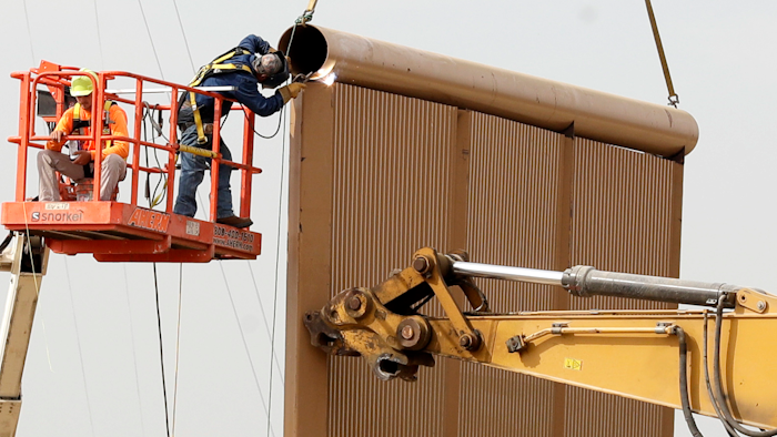 Crews work on a border wall prototype near the border with Tijuana, Mexico, Thursday, Oct. 19, 2017, in San Diego. Companies are nearing an Oct. 26 deadline to finish building eight prototypes of President Donald Trump's proposed border wall with Mexico.