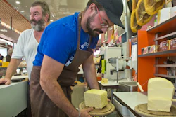 Nicolas Chatel takes away a piece of butter as Pierre Chatel stands behind him at the market in Marly le Roi, west of Paris.