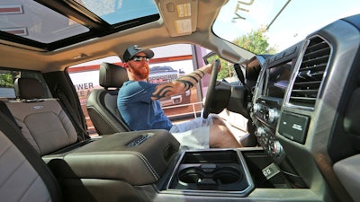 In this Monday, Oct. 9, 2017, photo, a man looks at the interior of a fully-loaded F-450 Super Duty Limited, the biggest version of the Ford F-Series, on display at the State Fair of Texas in Dallas. America's favorite luxury vehicle is a pickup truck. Buyers are increasingly outfitting their pickups with all the comforts of luxury cars, from heated and cooled seats to backup cameras to panoramic glass roofs.