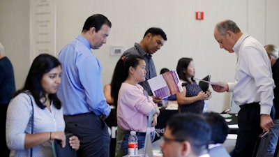 In this Thursday, Aug. 24, 2017, photo, Phil Wiggett, right, a recruiter with the Silicon Valley Community Foundation, looks at a resume during a job fair in San Jose, Calif. On Friday, Oct. 6, 2017, the U.S. government issues the September jobs report.