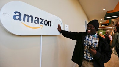 In this Monday, Oct. 16, 2017, photo, Zavian Tate, a student at the University of Alabama at Birmingham, pushes a large Amazon Dash button, in Birmingham, Ala. The large Dash buttons are part of the city's campaign to lure Amazon's second headquarters to Birmingham.