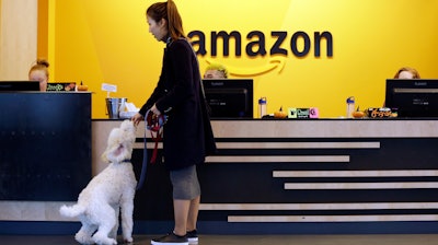 In this Wednesday, Oct. 11, 2017, photo, an Amazon employee gives her dog a biscuit as the pair head into a company building, where dogs are welcome, in Seattle. Whichever city lands Amazon’s second headquarters, some people in Seattle, it’s original hometown, say there are downsides to having the tech giant in the neighborhood.