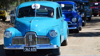 In this Oct. 15, 2017, historic Holden cars parade through the streets of Adelaide, Australia. The Australian auto manufacturing era ends after more than 90 years on Friday, Oct. 20, 2017 when General Motors Co.'s last Holden sedan rolls off the production line in the industrial city of Adelaide. The nation has already begun mourning the demise of a home-grown industry in an increasing crowded and changing global car market.