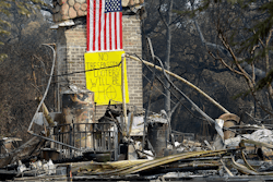 A sign on the chimney of a home warns looters Wednesday, Oct. 18, 2017, after it was destroyed by wildfires in Glen Ellen, Calif. California fire officials have reported significant progress on containing wildfires that have ravaged parts of Northern California.