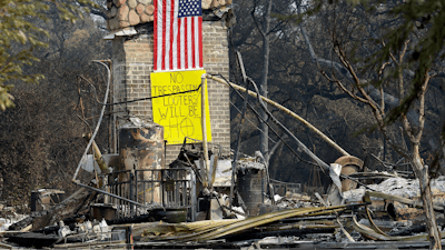 A sign on the chimney of a home warns looters Wednesday, Oct. 18, 2017, after it was destroyed by wildfires in Glen Ellen, Calif. California fire officials have reported significant progress on containing wildfires that have ravaged parts of Northern California.