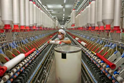 In this photo a worker prepares to load a cotton thread barrel into the machine at a textile factory in Huaibei in central China's Anhui province.