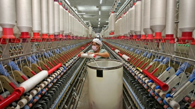 In this photo a worker prepares to load a cotton thread barrel into the machine at a textile factory in Huaibei in central China's Anhui province.