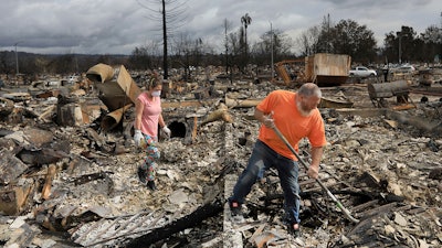 Sarah Boryszewski is helped by her father Gerald Peete as they dig for belongings in the remains of Boryszewski's home in Coffey Park, Friday Oct. 20, 2017 in Santa Rosa, Calif. Northern California residents who fled a wildfire in the dead of night with only minutes to spare returned to their neighborhoods Friday for the first time in nearly two weeks to see if anything was standing.