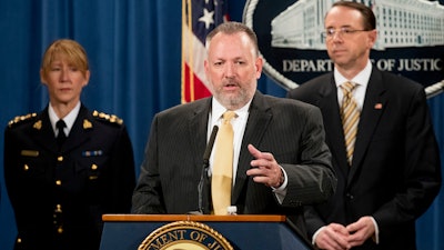 Drug Enforcement Administration Acting Administrator Robert Patterson, center, accompanied by Royal Canadian Mounted Police Assistant Commissioner Joanne Grace Crampton, left, and Deputy Attorney General Rod Rosenstein, right, speaks at a news conference at the Justice Department in Washington, Tuesday, Oct. 17, 2017, to announce the indictments of two Chinese fentanyl trackers in the fight against opiate substances from entering the United States.