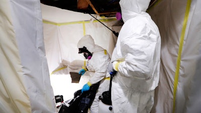 In this Oct. 18, 2017, photo, Asbestos Removal Technologies Inc., superintendent Ryan Laitila, right, sprays amended water, as job forman Megan Eberhart bags ceiling material during asbestos abatement in Howell, Mich. Spurred by the chemical industry, President Donald Trump’s administration is retreating from a congressionally mandated review of some of the most dangerous chemicals in public use. The review began under Trump’s predecessor to make sure proper safeguards are in place for asbestos and other toxins in homes, offices and industrial plants across the United States.