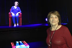 In this Oct. 20, 2017 photo, Holocaust survivor Fritzie Fritzshall poses for a portrait in front of her 3D hologram at the Illinois Holocaust Museum in Skokie, Ill. Fritzshall is one of 13 Holocaust survivors who tell their stories through holographic images that invite the audience to ask questions, creating what feels like a live conversation. The exhibit in Skokie marks the first time that the voice-recognition technology powering conversations with audiences has been married to 3-D holographic technology to tell survivors' stories.