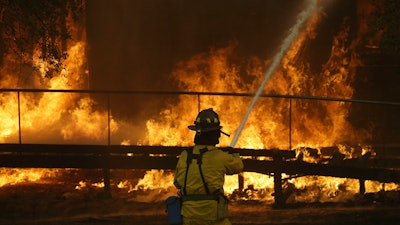 In this Oct. 9, 2017 file photo, a firefighter sprays a hose into a Keysight Technologies building in Santa Rosa, Calif. The Santa Rosa Press Democrat reported that more than 100 boxes of letters and other materials from tech pioneers William Hewlett and David Packard burned in the fires. Electronics firm Keysight Technologies had acquired the archives through spinoffs, and the archives were stored at its offices in Santa Rosa.